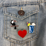 Een toekan rood hart en een blauwe cocktail pin op een borstzakje van een blauwe spijkerjas