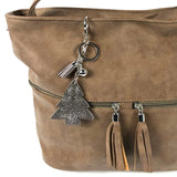 Close-up van een luxe zilverkleurige sleutelhanger met een hanger van een dennenboom van strass steentjes aan een benige dames handtas