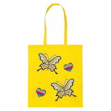 Twee maal de Hart Regenboog Glitter Strijk Embleem Patch samen met twee vlinder strijk patches op een  geel linnen tas