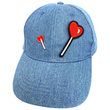 Lolly Hartje Emaille Pin samen met de lolly strijk patch op een op een cap van spijkerstof