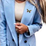 Broche Sierspeld Vlinder Blauw Groen Geel Paars op een blauwe colbert / jas