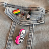 Geraamte Skelet Emaille Pin Knal Roze samen met drie andere emaille pins op een spijkerjasje