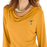 Broche Sierspeld Kolibrie Vogel Groen Oranje op een mosterdgeel shirt