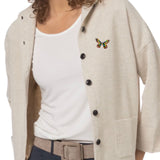 Broche Sierspeld Vlinder Blauw Groen Geel Paars op een beige vest
