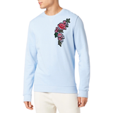 Rozen Bloemen Tak XXL Strijk Embleem Roze Links op een lichtblauwe sweater