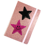 Donker Roze Smiley Glitter Ster Strijk Embleem Patch samen met een zwarte paillette ster strijk patch op de voorzijde van een glitter roze agenda