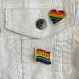 Close up van de Rainbow Heart Regenboog Hartje Gay Pride Symbool Emaille Pin samen met een regenboog vlag pin