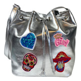 Girl Tekst Kroon Strijk Embleem Patch Roze samen met drie andere strijk patches op een zilverkleurige tas