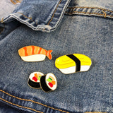 Emaille Pin / Speld Van Twee Gevulde Sushi Rolletjes samen met twee andere sushi speldje op een blauw spijkerjasje