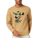 Vlinder Strijk Embleem Patch Donker Bruin samen met een groen bloesem bloemen tak op een mosterdgele sweater