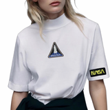Nasa Tekst Embleem Strijk Patch Goud Zwart samen met een space pilot strijk patch op een wit t-shirt
