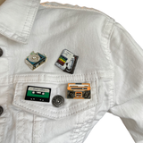 Cassettebandje Cassettedeck Tape Emaille Pin samen met andere pins van geluid beeld dragers op een wit spijkerjasje
