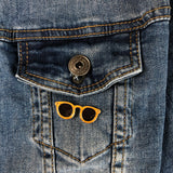 Oranje zonnebril pin op een borstzakje van een blauw spijkerjasje