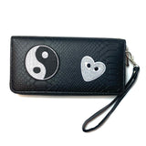 Ronde Yin Yang Strijk Embleem Patch samen met een zilverkleurig hartje strijk patch op een zwarte portemonnee