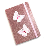 Twee Roze Witte Paillette Vlinder Strijk Patches op de voorkant van een glitter roze agenda
