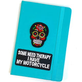 Some Need Therapy I Have My Motorcycle Tekst Strijk Embleem Patch En een zwarte sugar skull strijk patch op de voorzijde van een blauwe agenda
