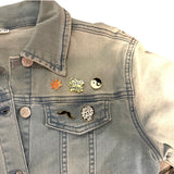 Yin Yang Emaille Pin samen met vier andere emaille pins op een spijkerjack