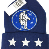 Ovaal blauwe patch van een astronaut die tussen desserten zweeft op een blauwe muts met drie zilverkleurige sterren