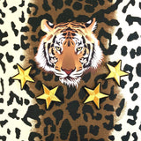 Vier Goud kleurige Strijk Ster Patches samen met een tijgerkop applicatie op een sierkussen met dierenprint