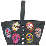 zes verschillend gekleurde sugar skull patches op een grijze vilten tas.