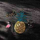 Close-up van een zwarte poes pin cool tekst pin en flamingo pin samen met een Anas patch op een zwart glimmend jasje