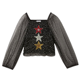 Ster Strass Ster Patch Goud samen met een rode en zilverkleurige variant van deze patch op een zwart wit gestippeld blouse met doorzichtige mouwen  