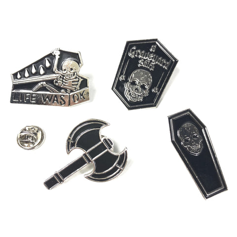 vier zwart met zilverkleurige pins die samen de graveyard Helloween pin set vormen twee grafkist pins met doodskop afbeelding een grafsteen pin met doodskop en een pin van een gevechtsbijl 